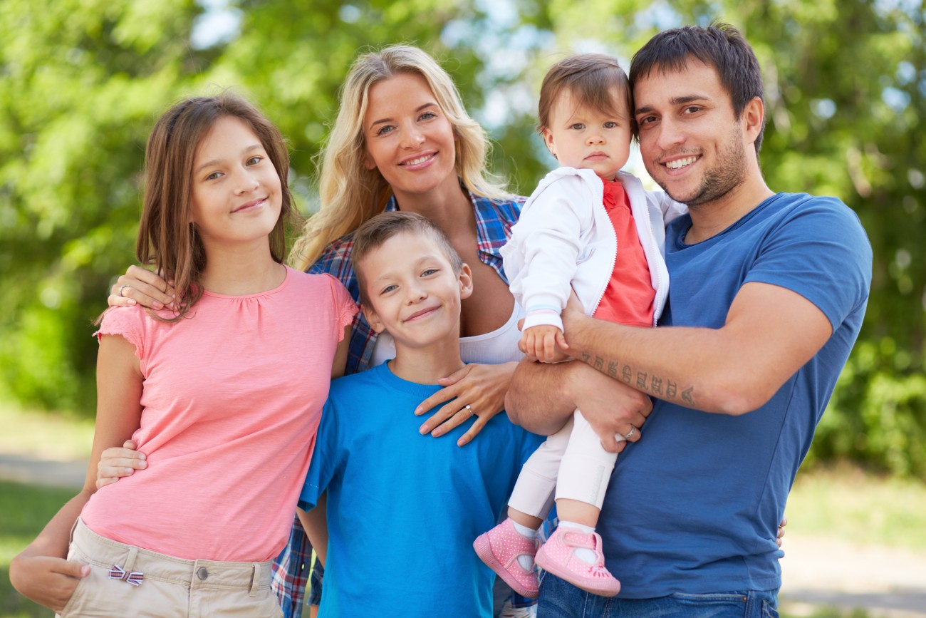 Photo of happy family looking at camera outdoors